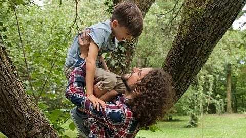 father lifting boy in forest